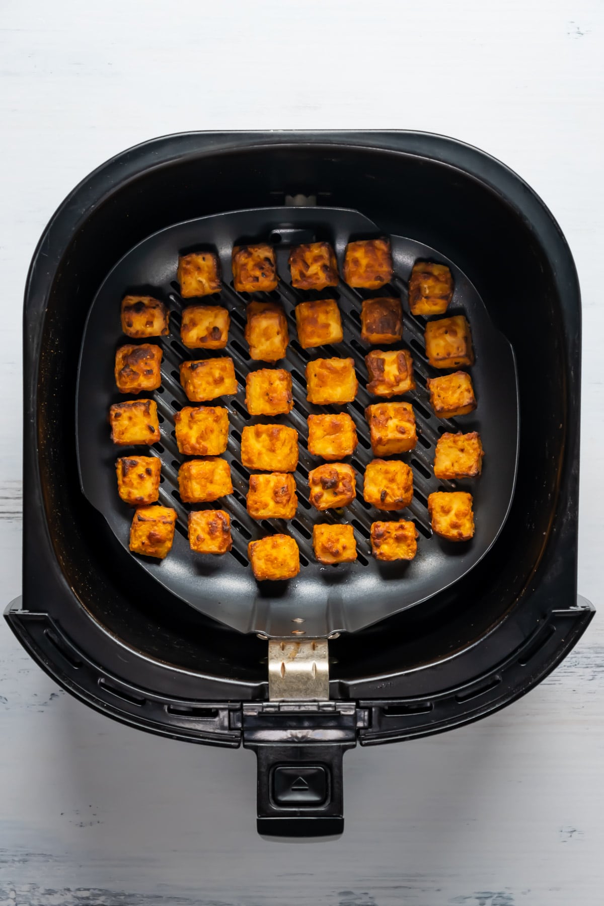 Blocks of tofu in an air fryer.