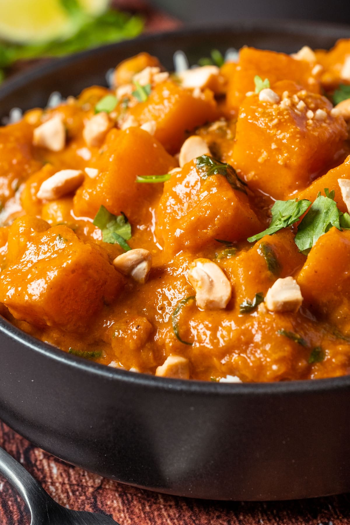 Vegan butternut squash curry with rice in a black bowl.