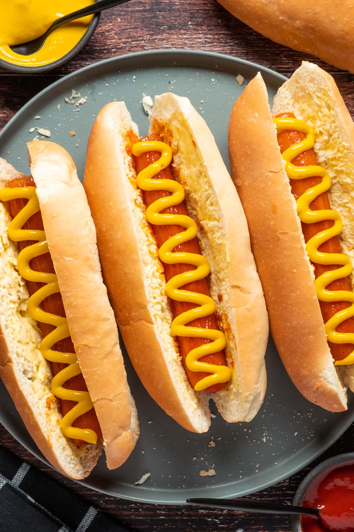 Carrot dogs with mustard on a gray plate.