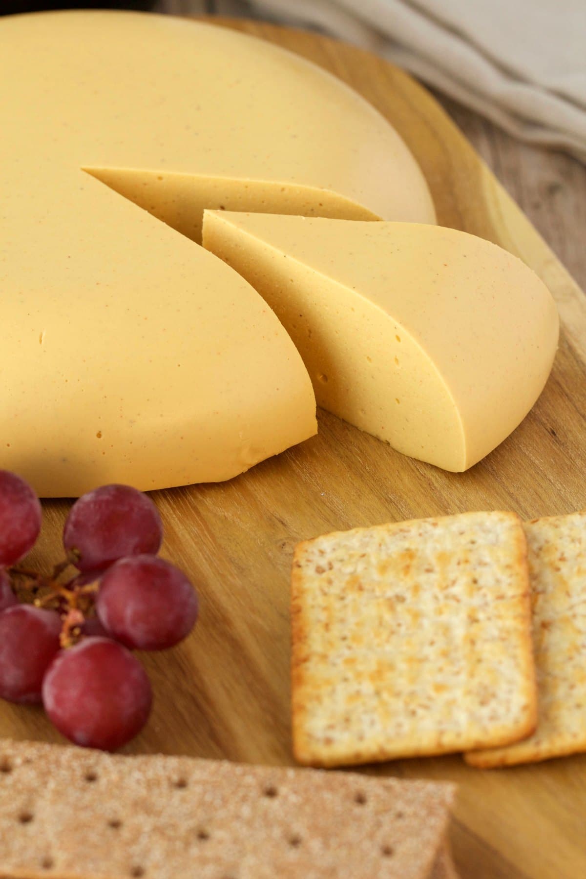 Vegan cheese on a cheese board with red grapes and crackers. 