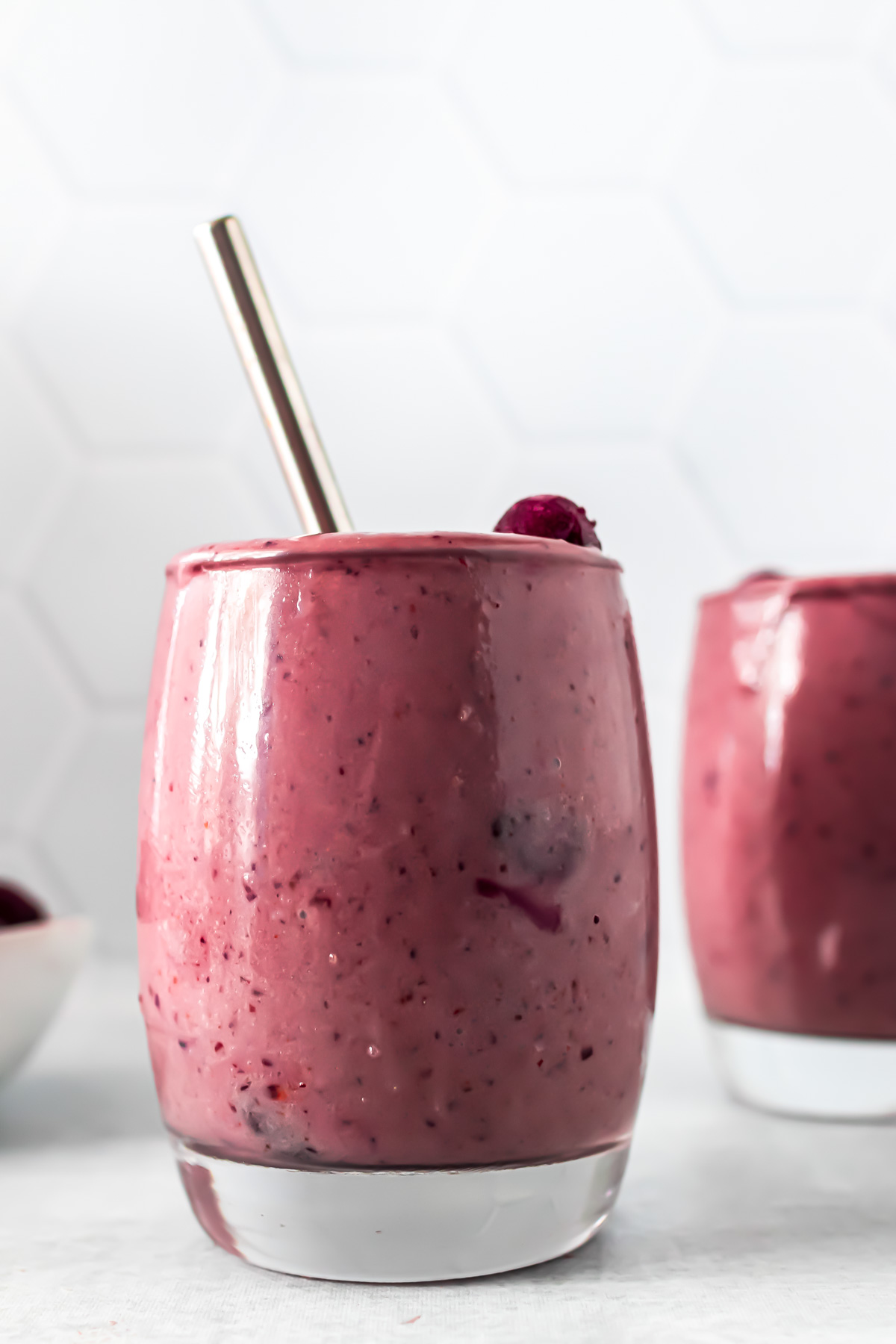 Cherry smoothie in a glass with a straw.