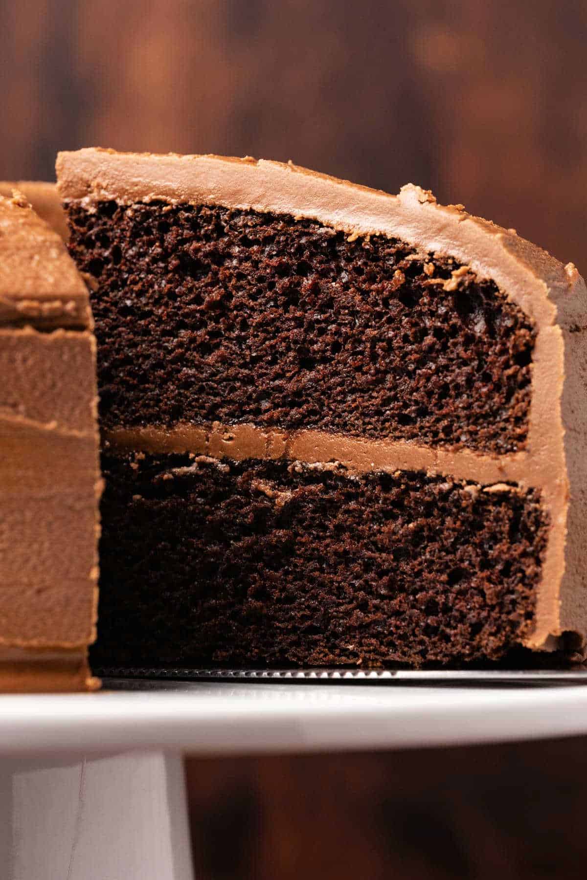 Cake on a white cake stand with one slice ready to serve. 