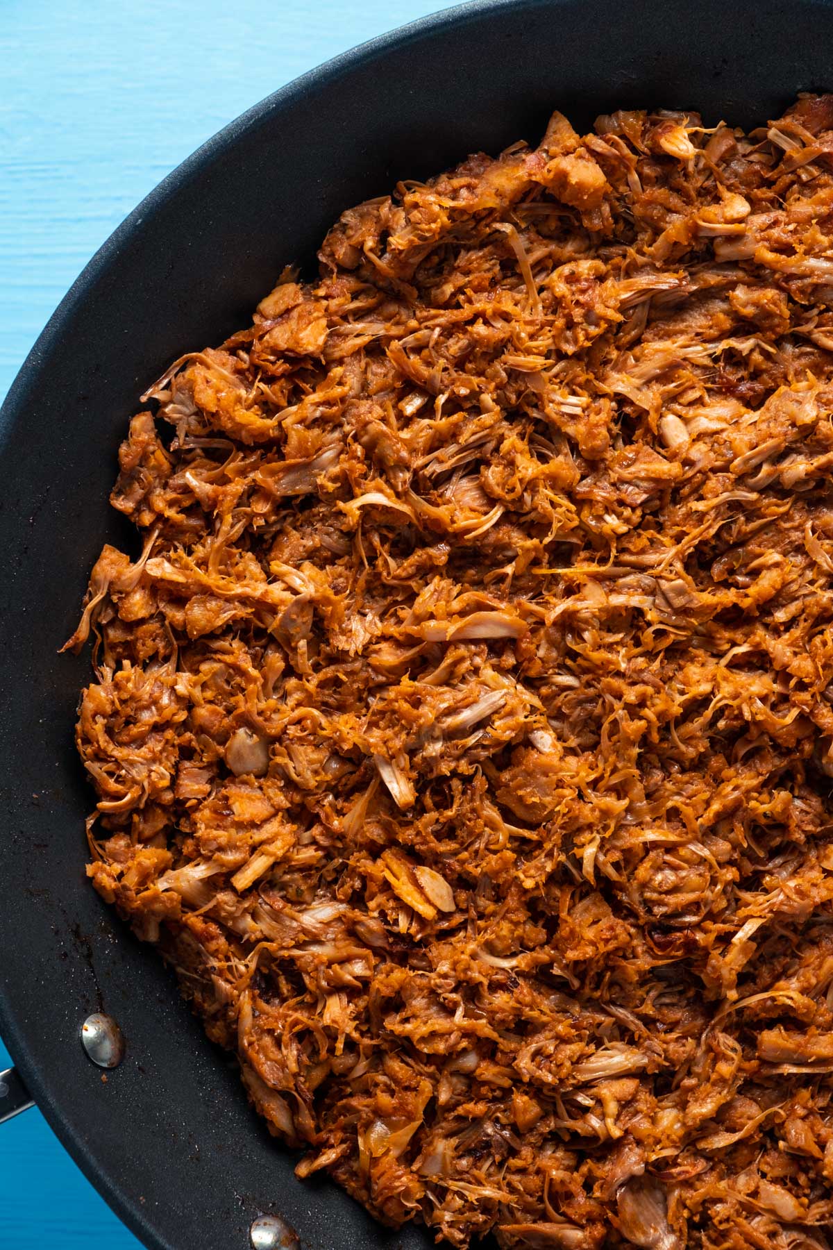 Cooked, shredded jackfruit in a frying pan.