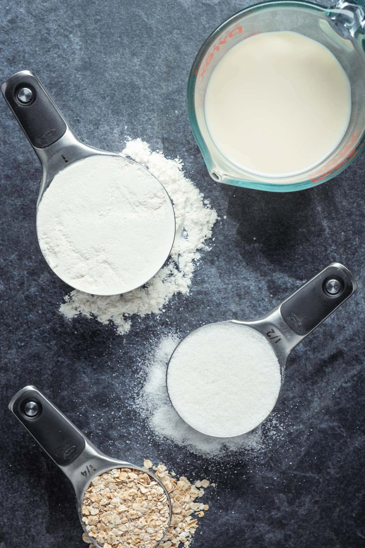 Flour, sugar, oats and soy milk in measuring cups. 