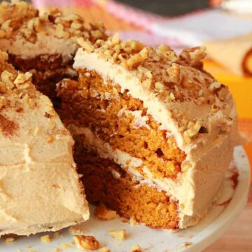 Vegan pumpkin cake on a white cake stand.