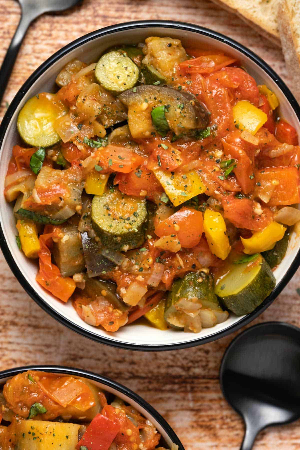 Ratatouille topped with black pepper and dried oregano in a ceramic bowl. 