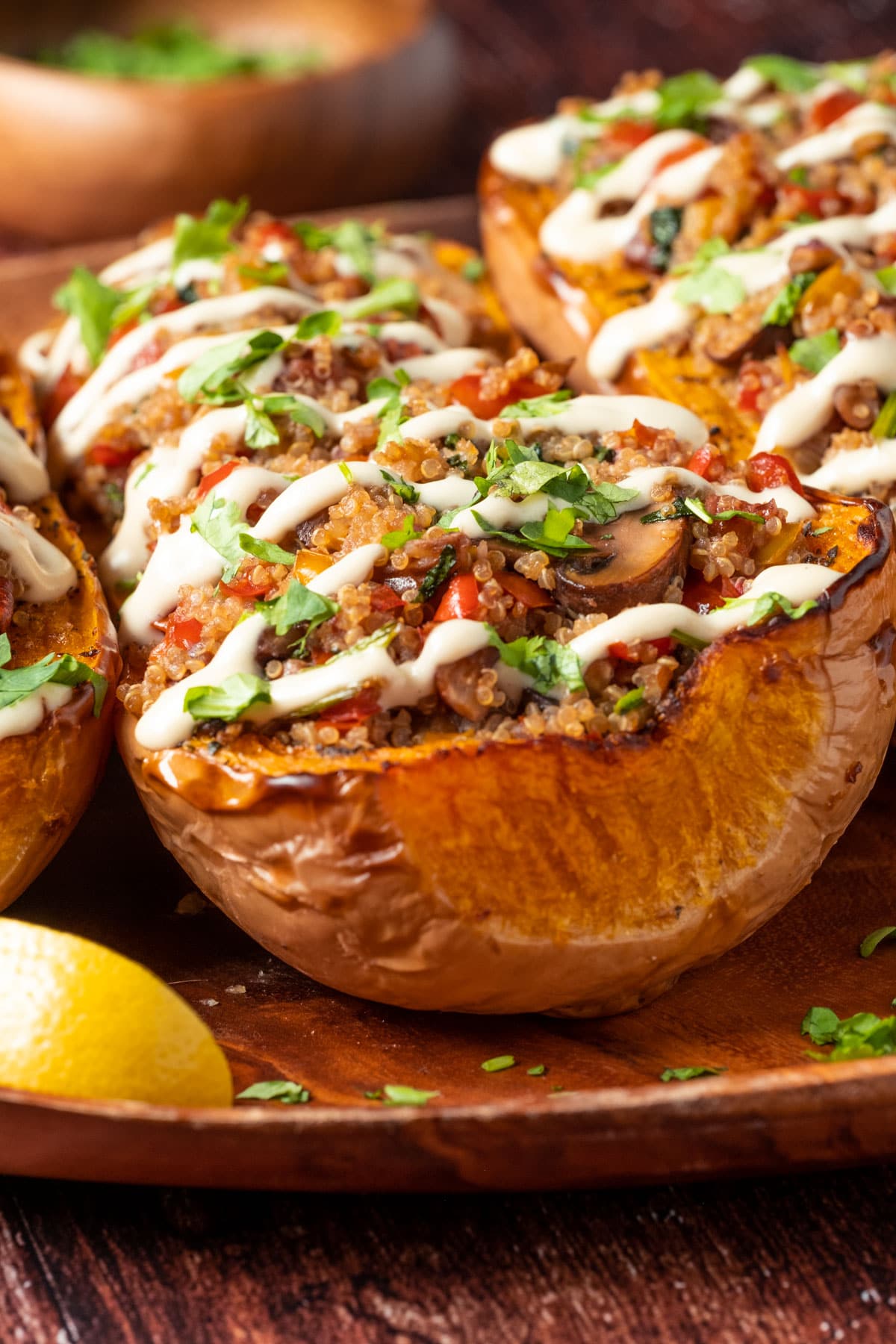 Stuffed butternut squash drizzled with cashew cream and sprinkled with fresh chopped cilantro on a serving platter.