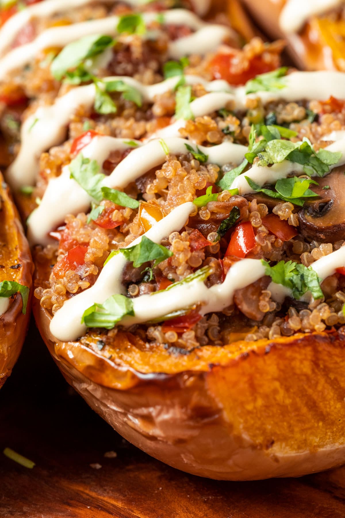 Stuffed butternut squash drizzled with cashew cream and sprinkled with fresh chopped cilantro on a serving platter.