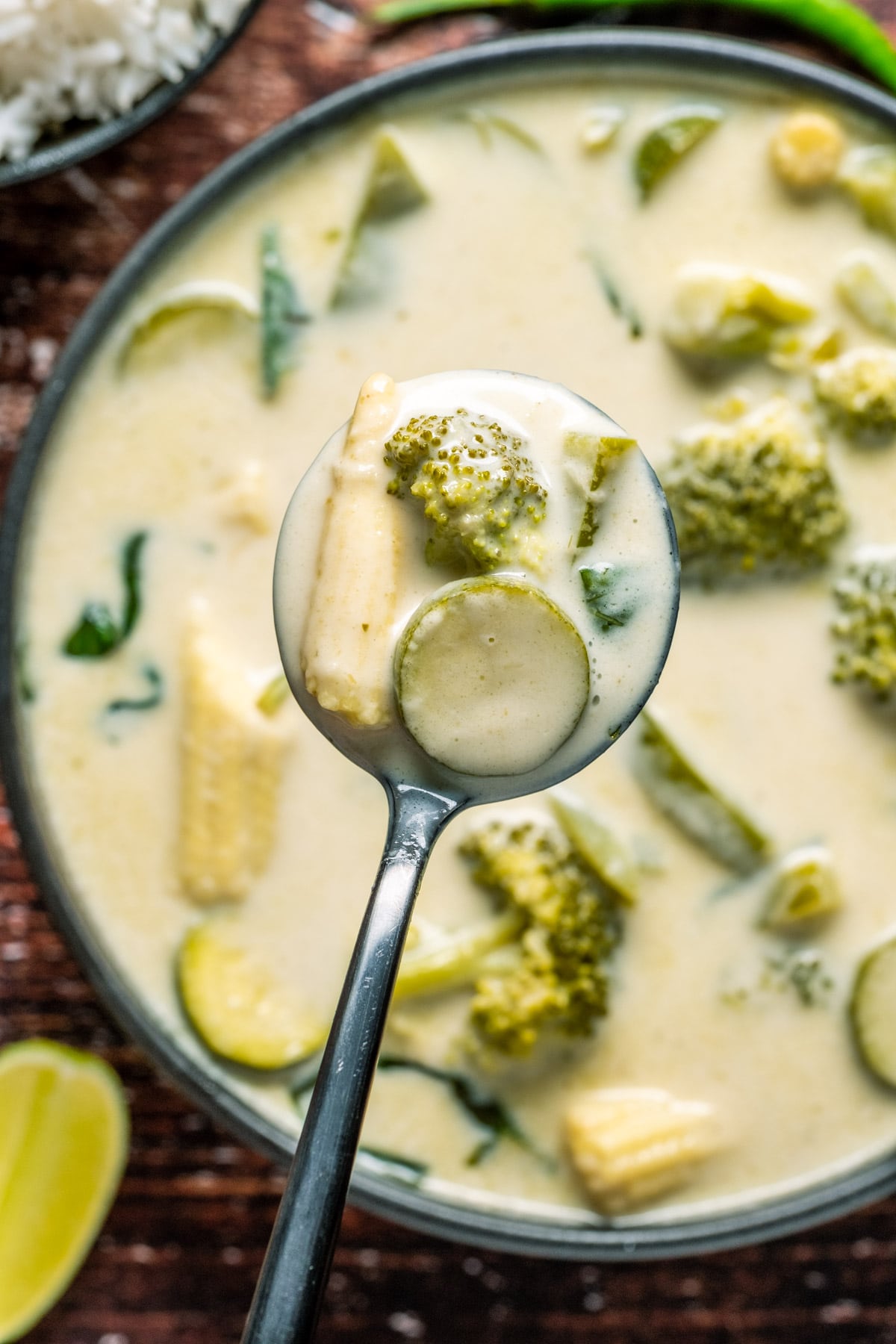 Vegan Thai green curry in a black bowl with a spoon.