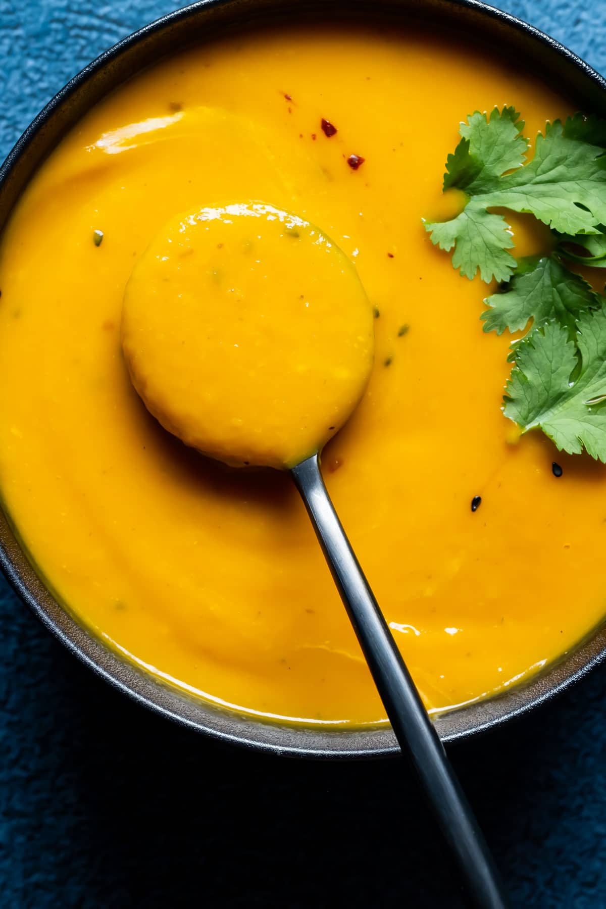 Thai sweet potato soup in a black bowl with a spoon.