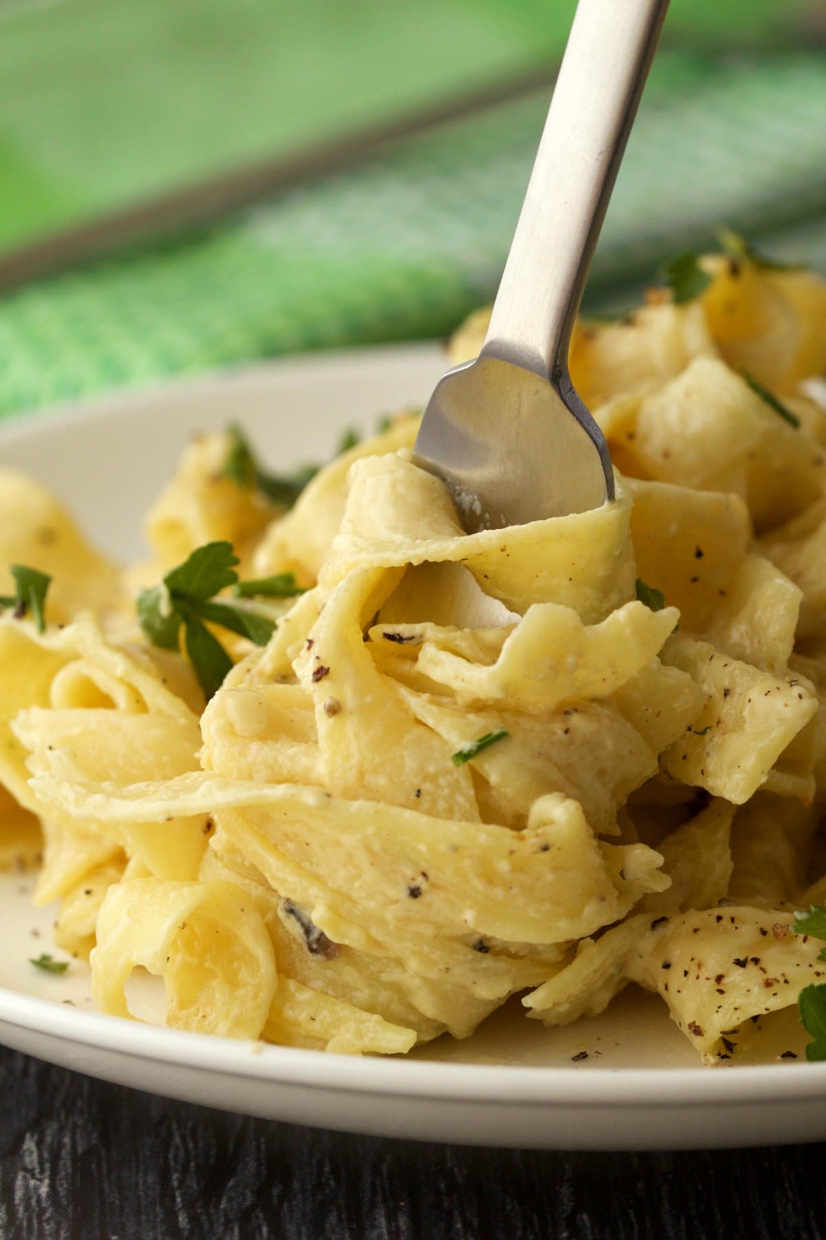 Vegan fettucine alfredo on a white plate with a fork. 