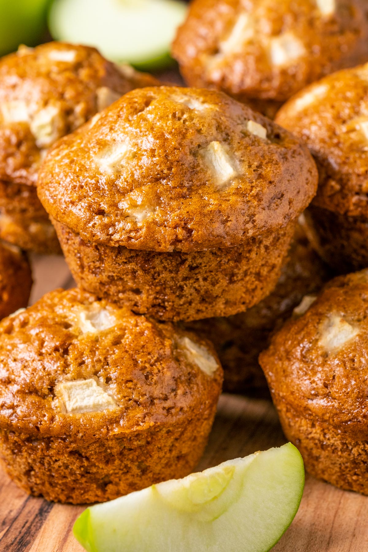 Vegan apple muffins stacked up on a wooden board. 