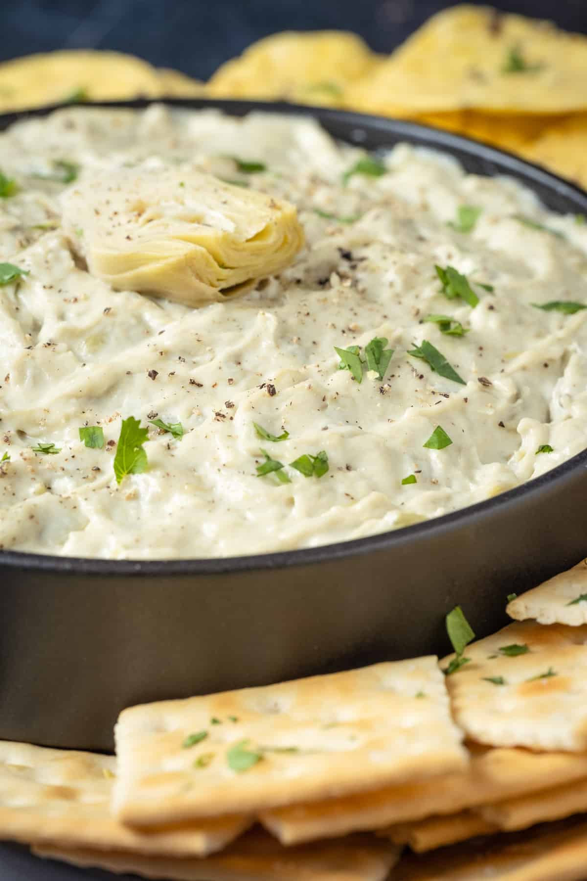 Vegan artichoke dip in a black bowl.