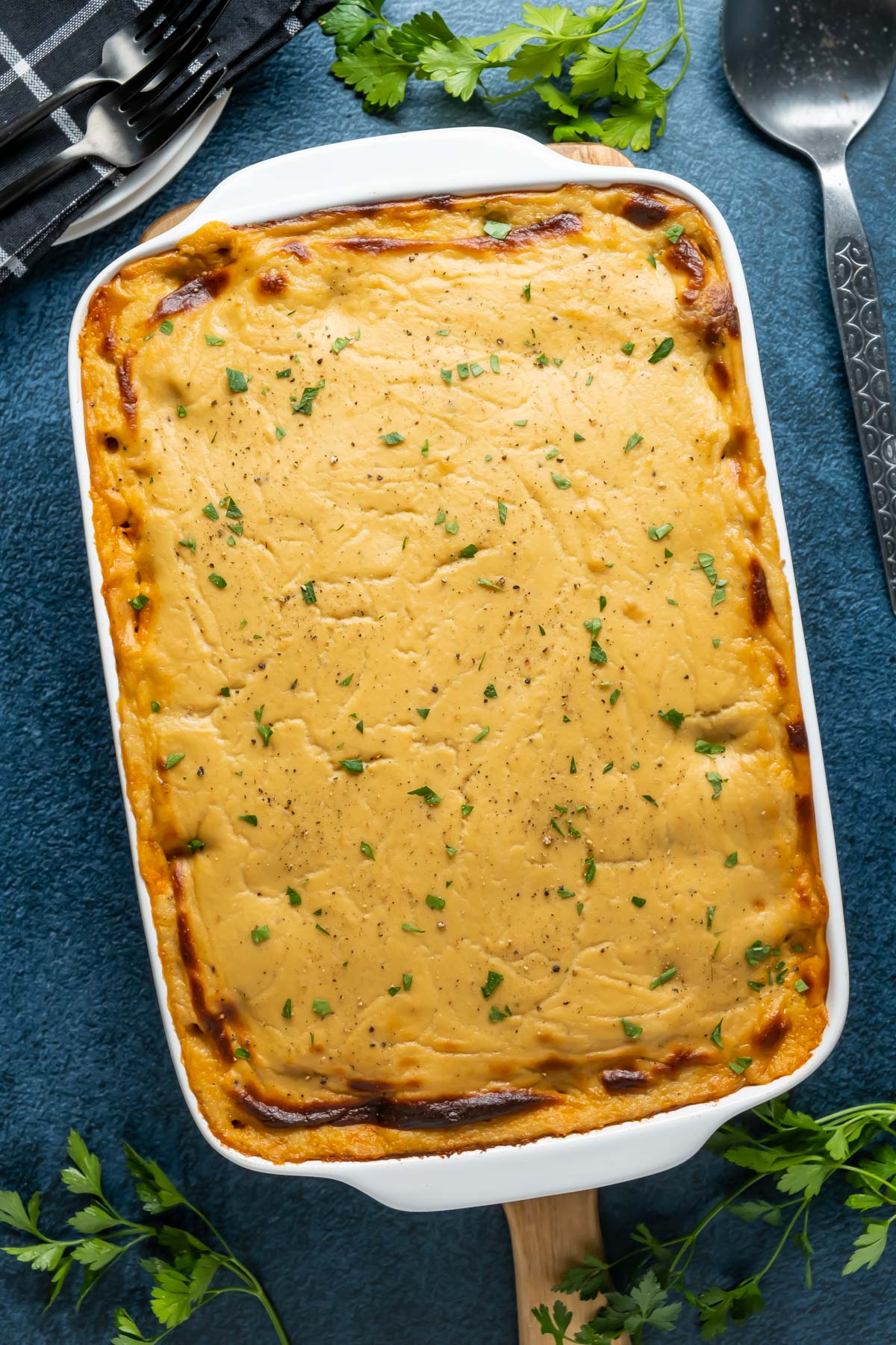 Vegan baked ziti topped with fresh chopped parsley in a white dish.