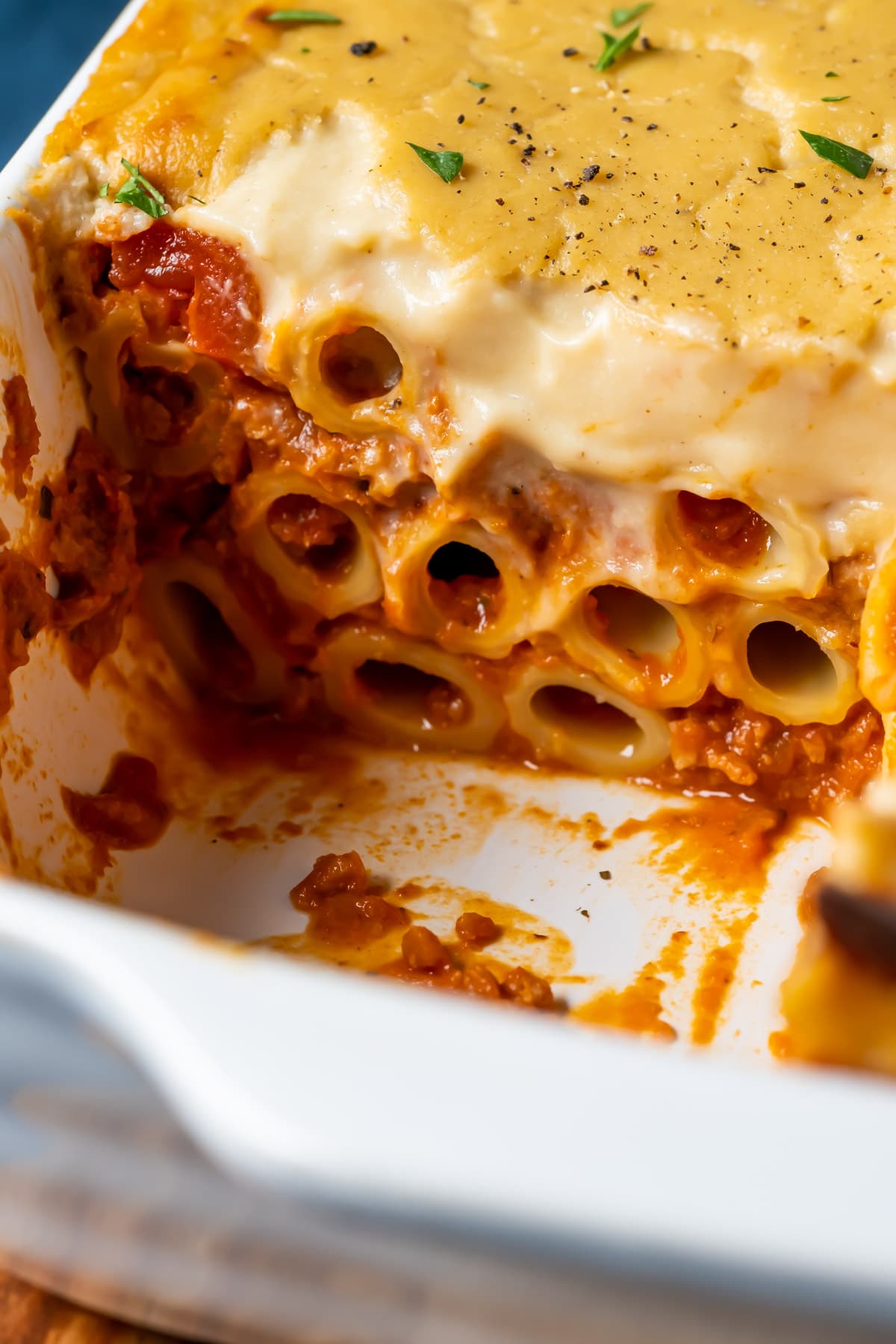 Vegan baked ziti with one slice removed, in a white dish.