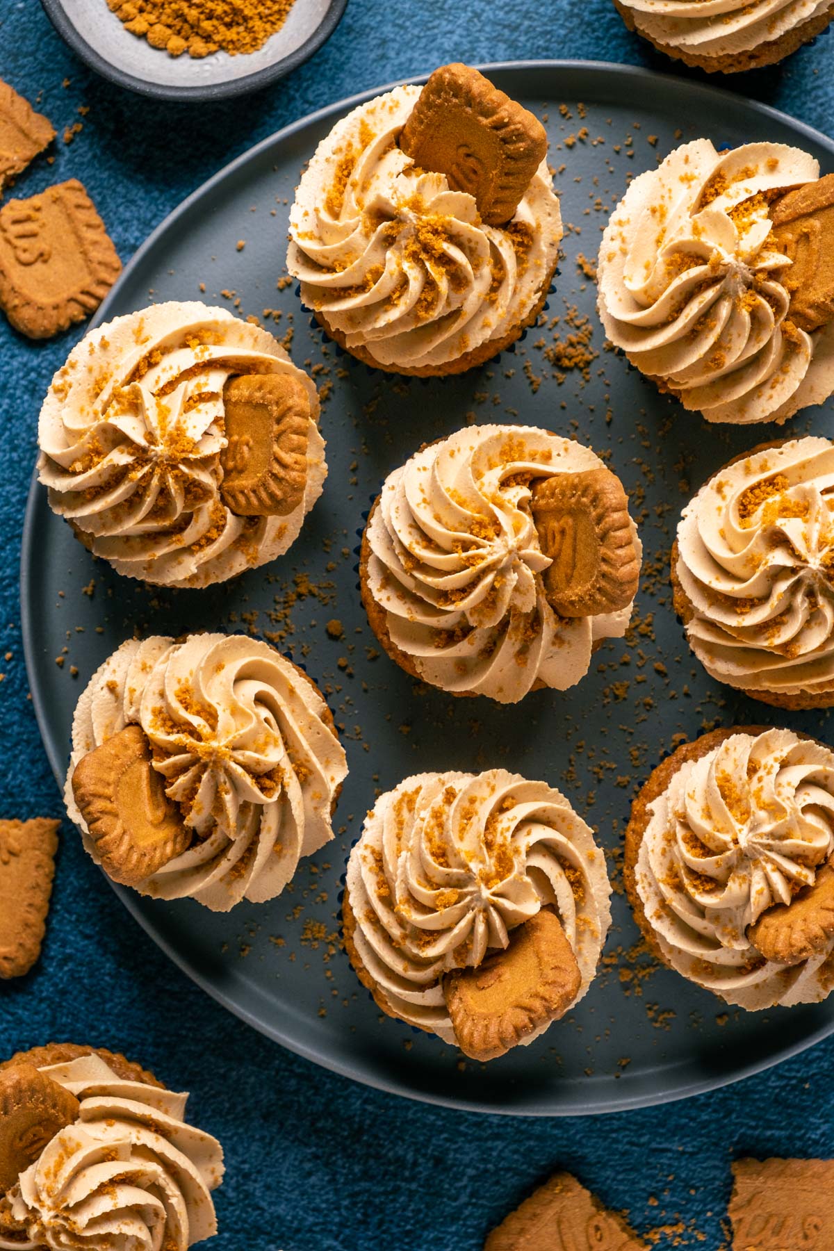 Frosted and decorated vegan biscoff cucpakes on a gray plate.