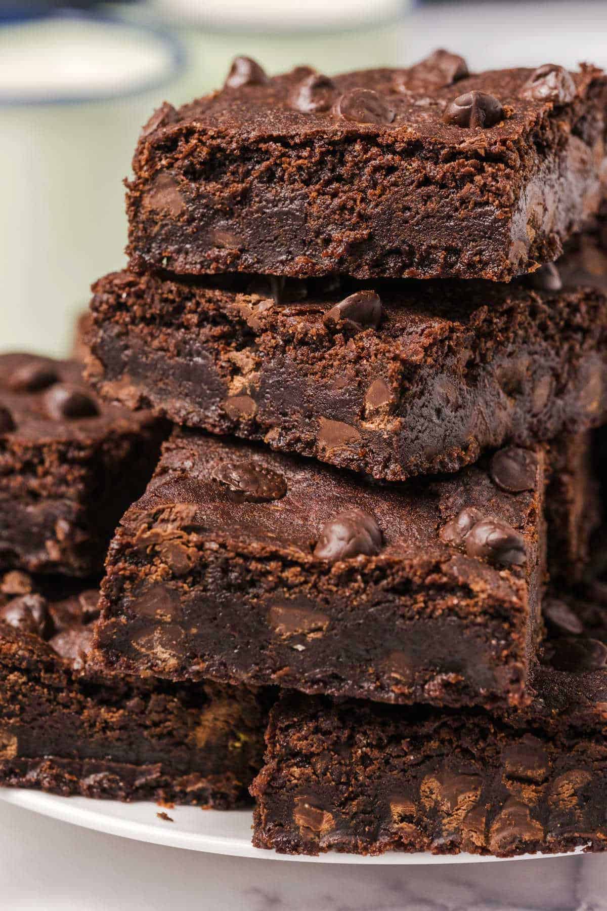 Brownies stacked up on a white plate. 