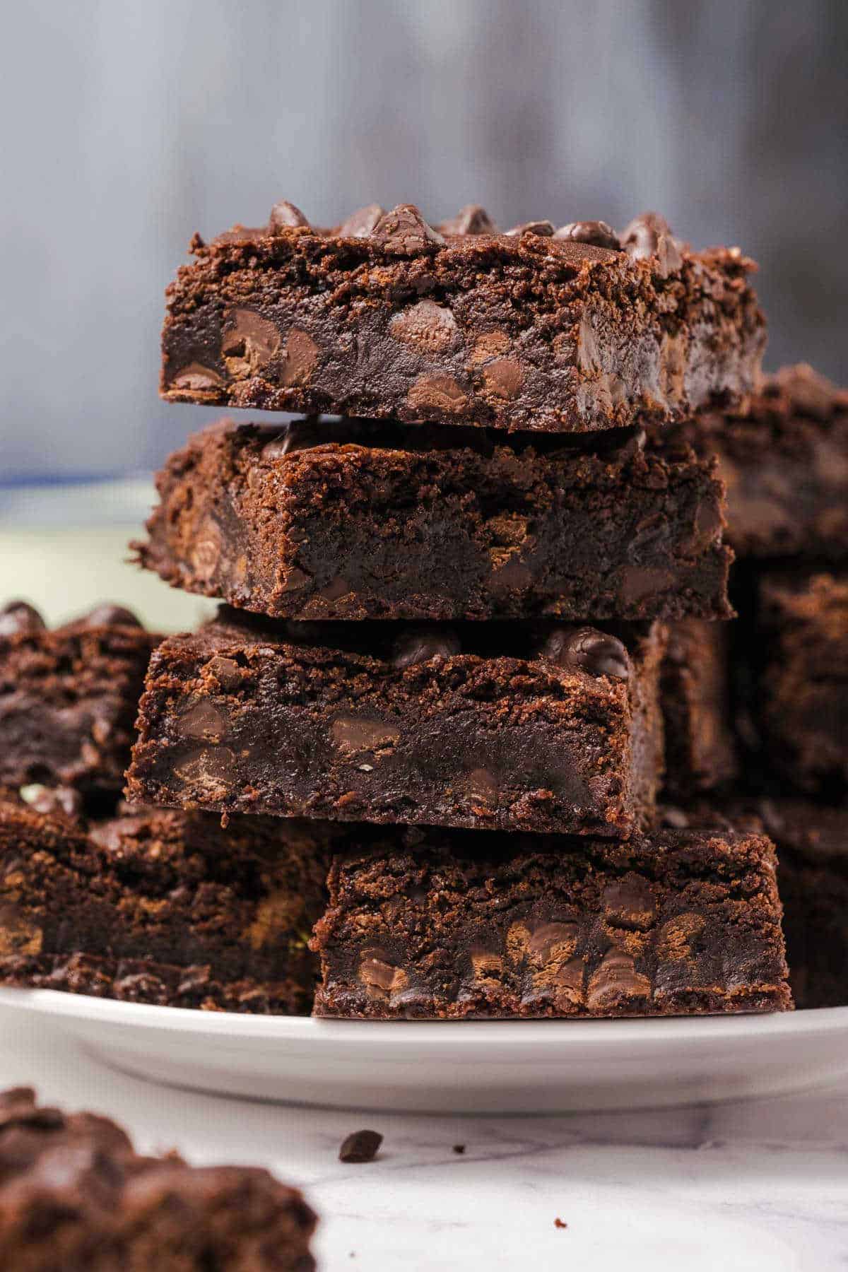 Brownies stacked up on a white plate.