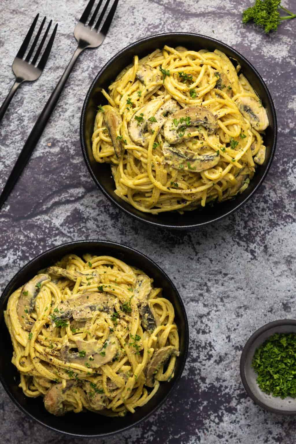 Vegan carbonara in black bowls. 