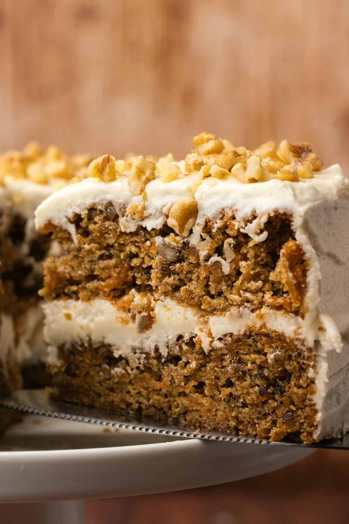 Sliced carrot cake on a white cake stand.