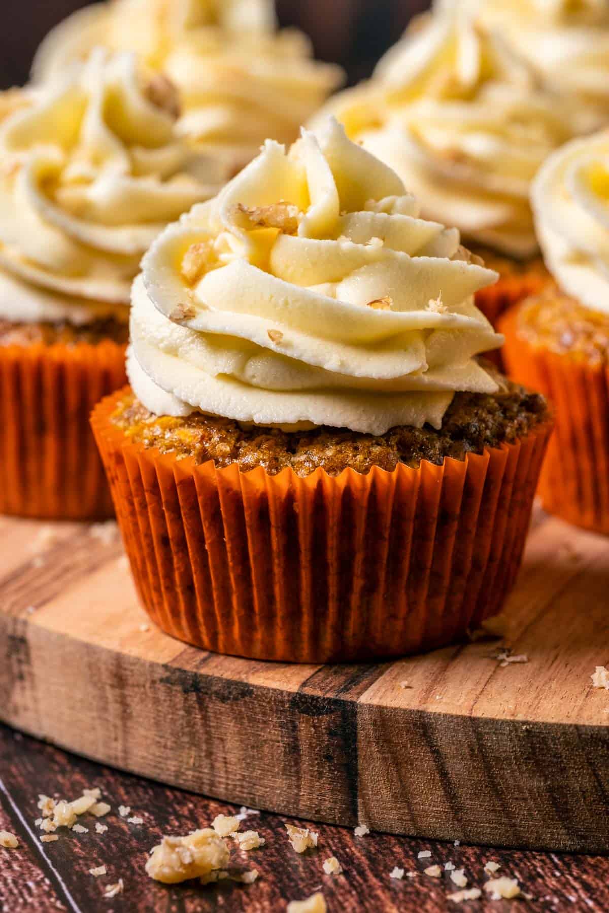 Vegan carrot cake cupcakes on a wooden board.