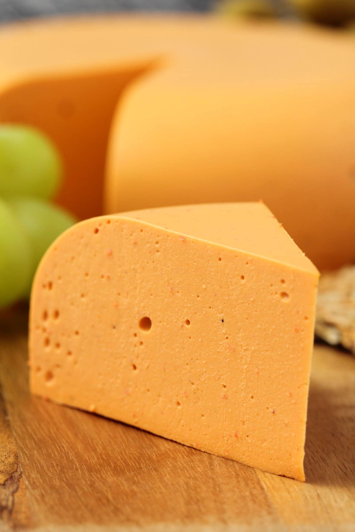 Vegan cheddar cheese on a cheese board with grapes and crackers. 