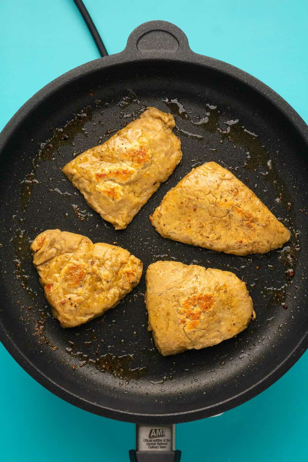 Vegan chicken fillets frying in a frying pan. 