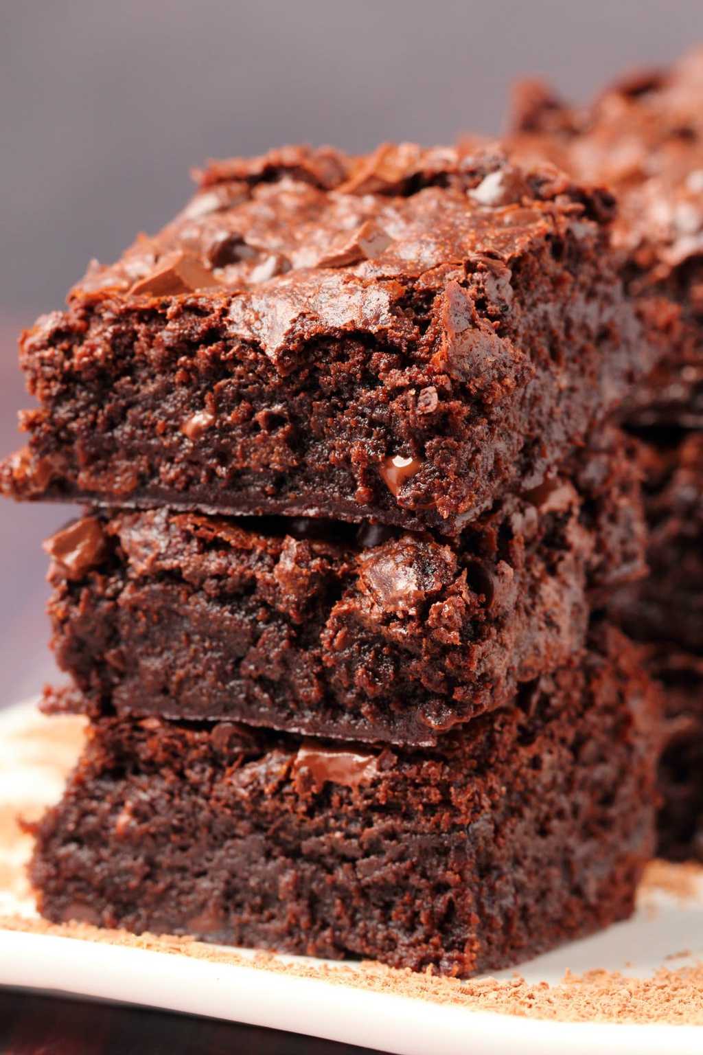 Vegan chocolate brownies stacked up on a white plate. 