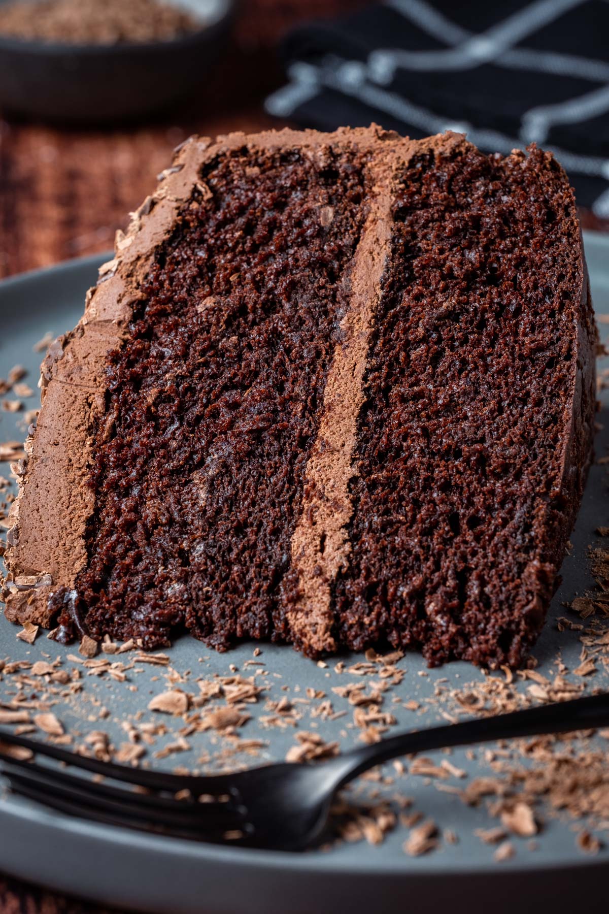 Slice of vegan chocolate fudge cake on a gray plate with a cake fork.