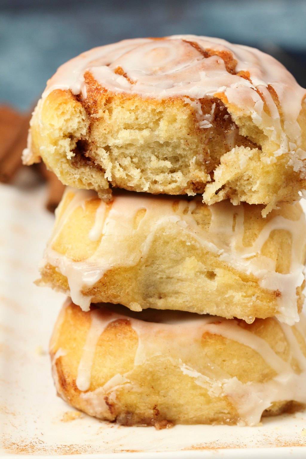 Vegan cinnamon rolls in a stack with the top one broken in half to show the center. 