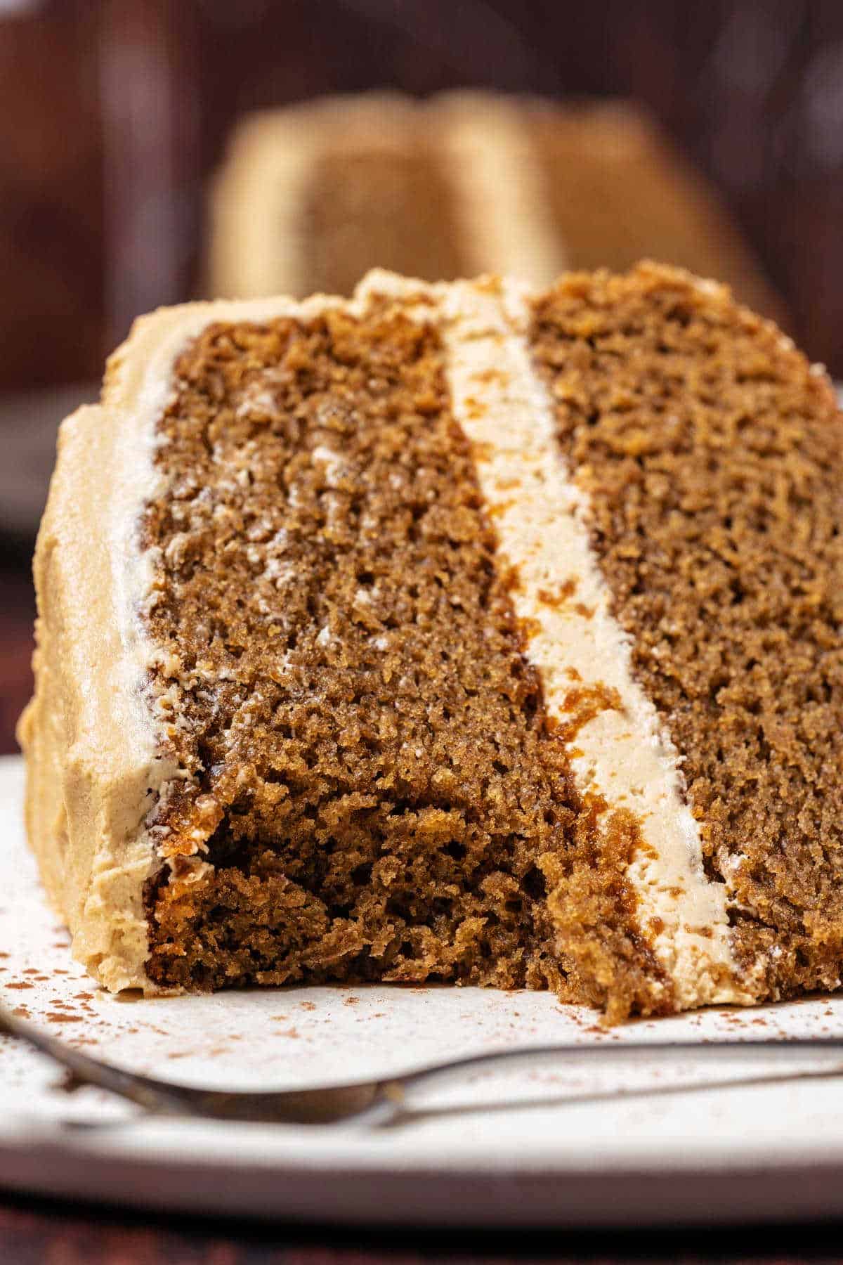 Slice of coffee cake on a white plate with a bite removed.