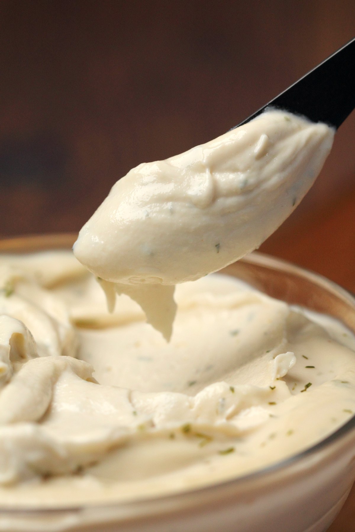 Vegan cream cheese in a glass bowl with a knife. 