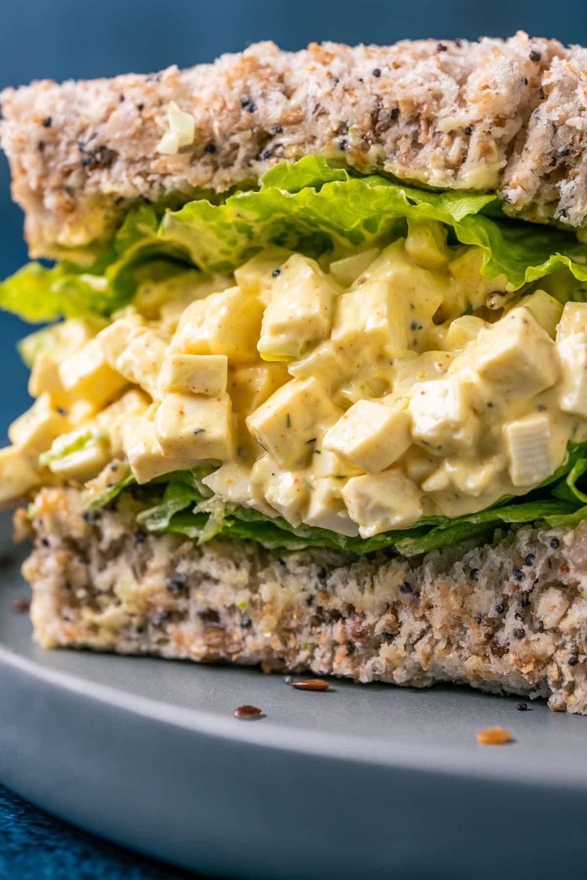 Vegan egg salad sandwich cut in half on a gray plate.