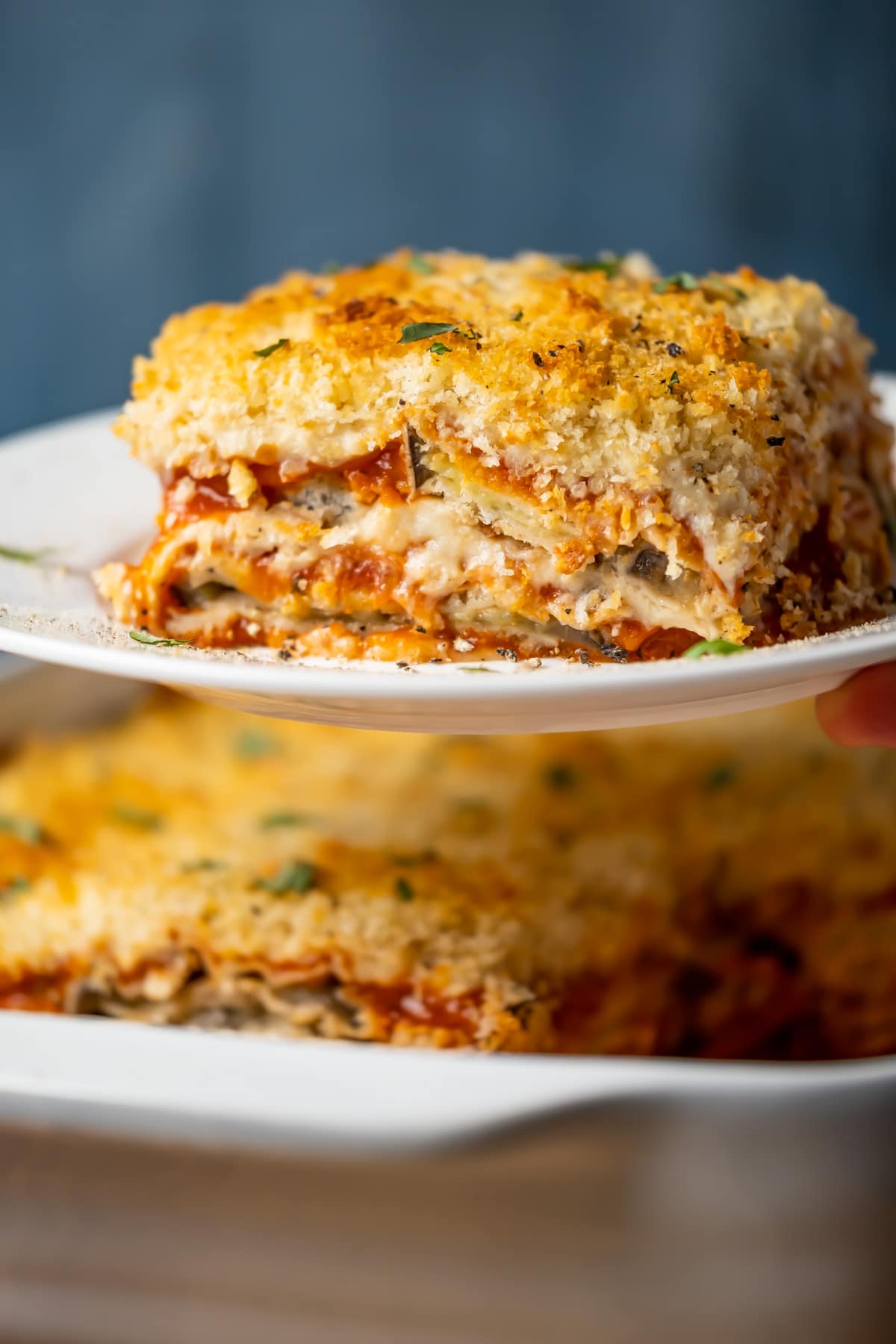 Slice of vegan eggplant parmesan on a white plate.