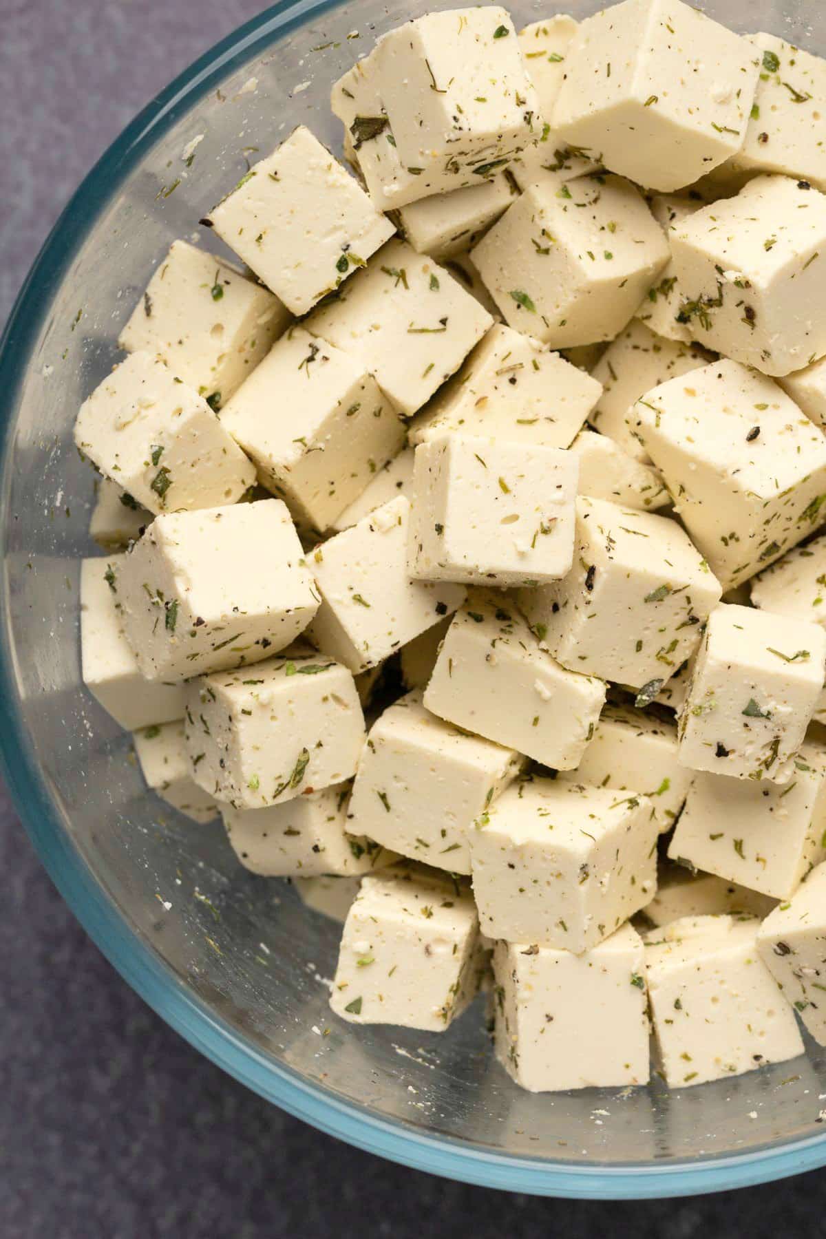 Vegan feta and dried herbs in a glass bowl.