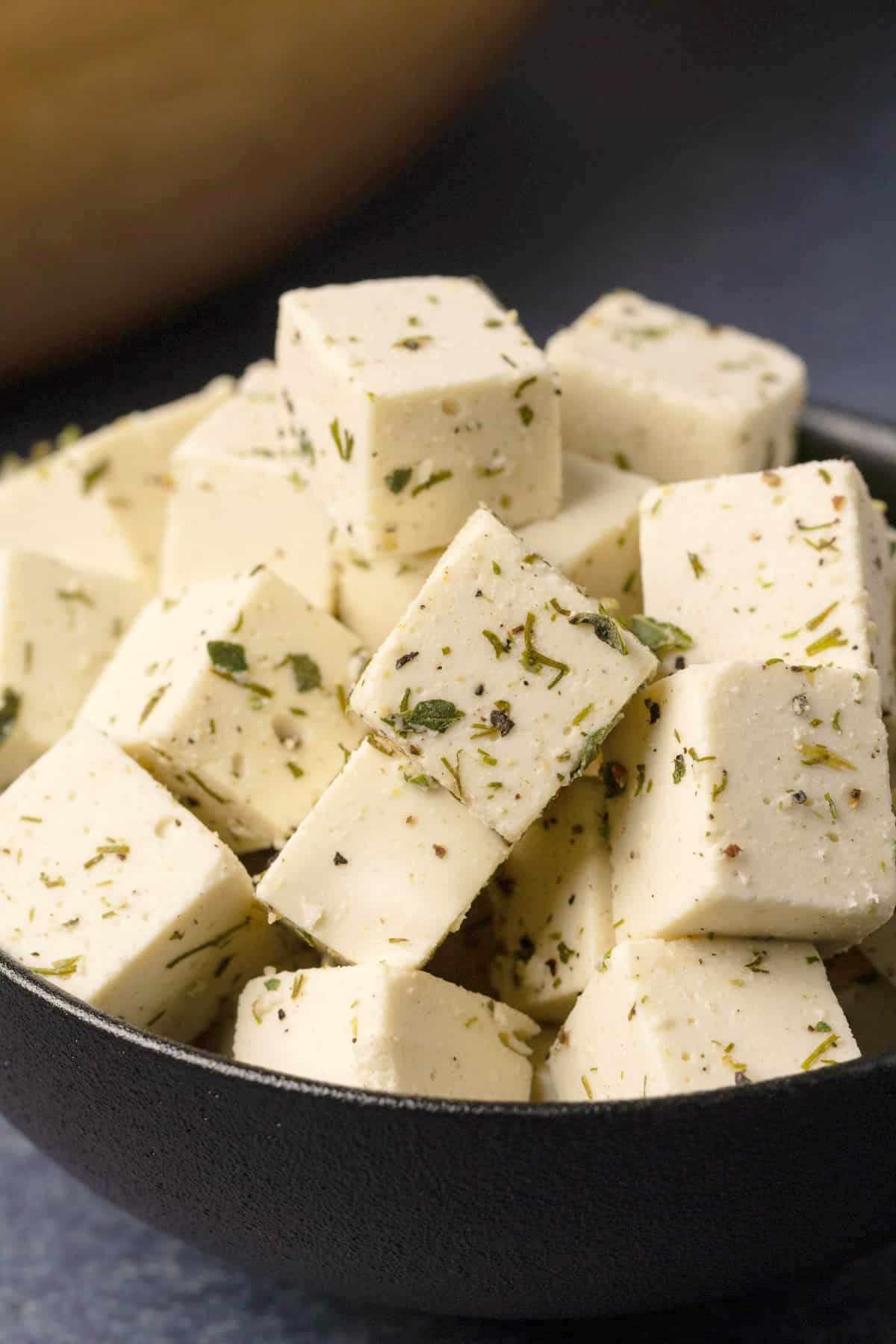 Cubes of vegan feta cheese in a black bowl.