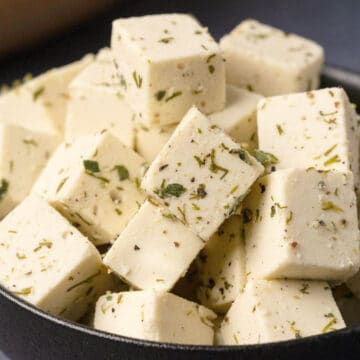 Cubes of vegan feta cheese in a black bowl.
