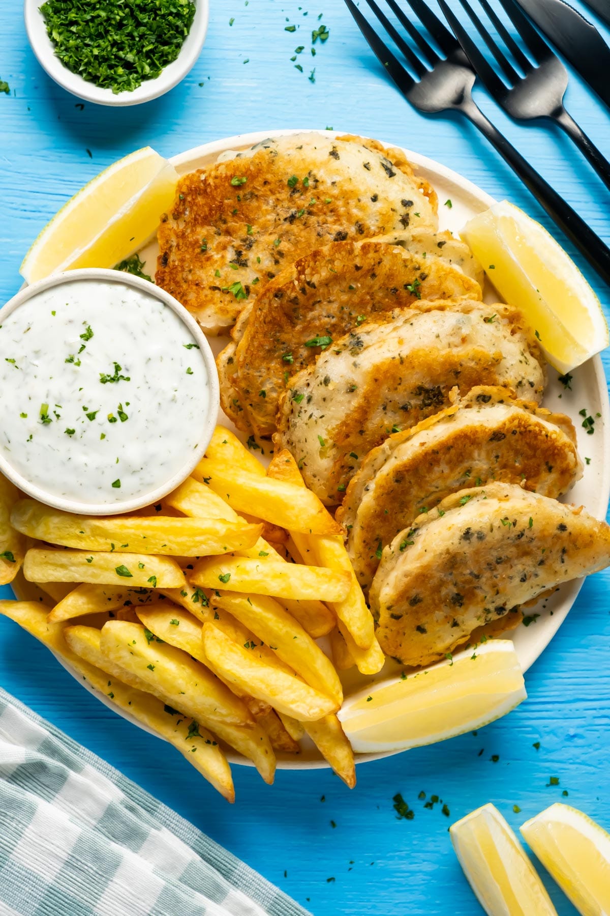 Beer battered vegan fish with chips, vegan tartar sauce and fresh lemon on a plate. 