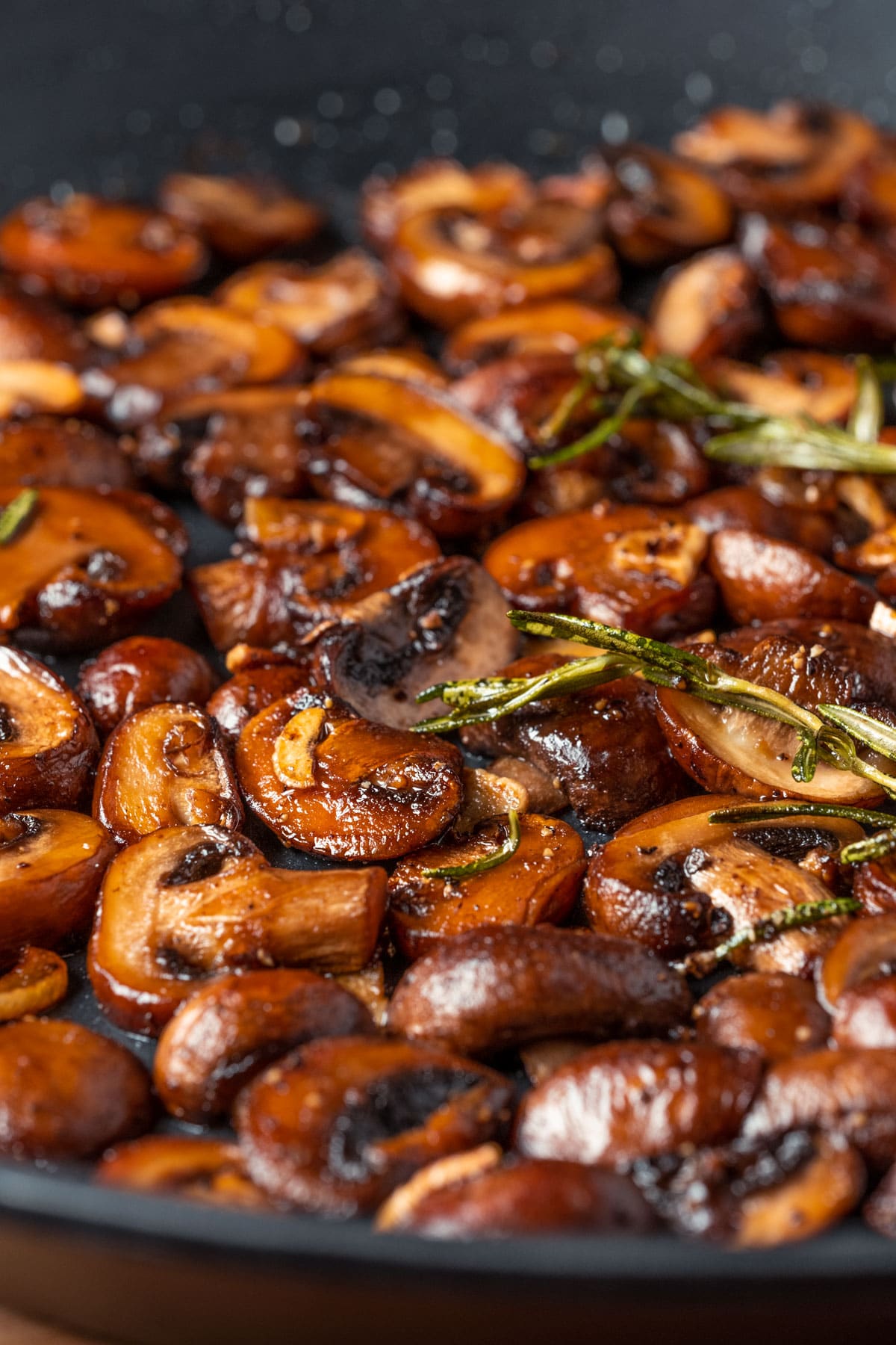 Vegan garlic mushrooms in a skillet with rosemary.