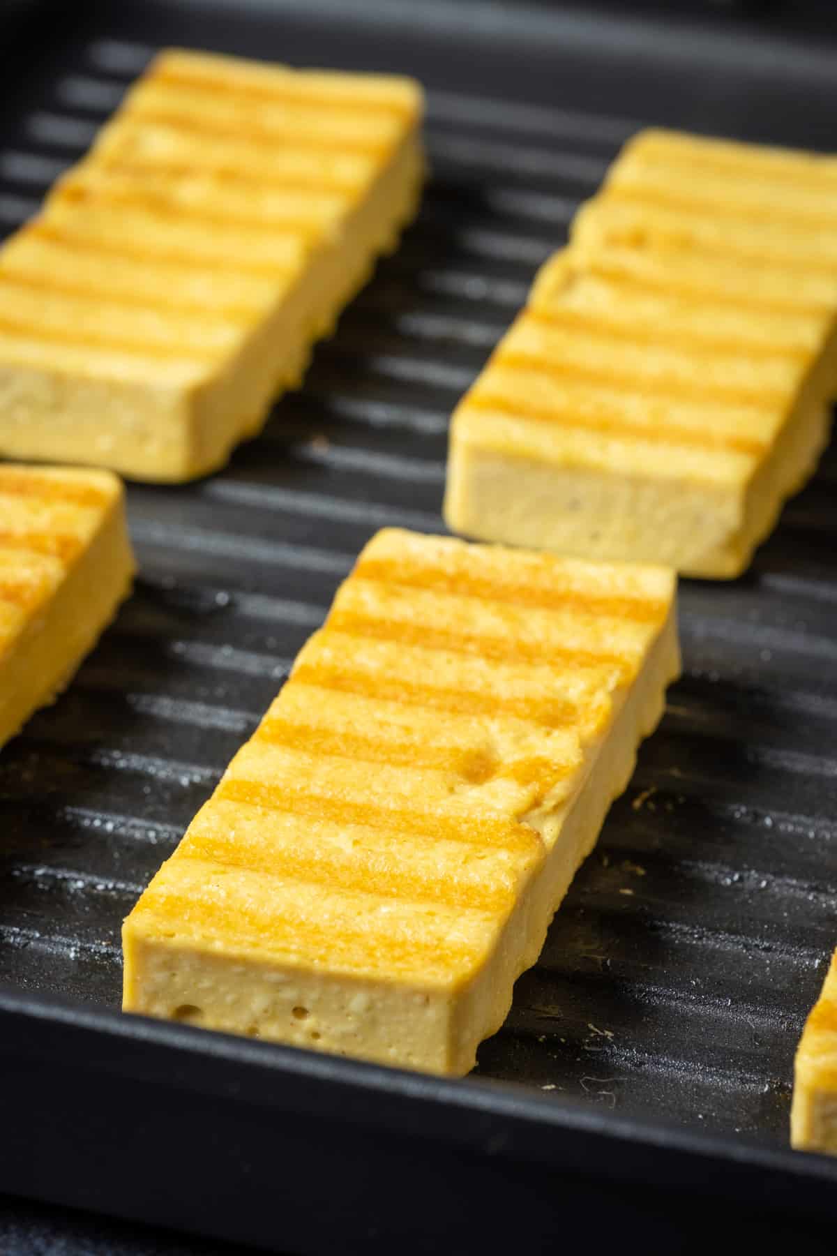 Vegan halloumi slices in a grill pan.