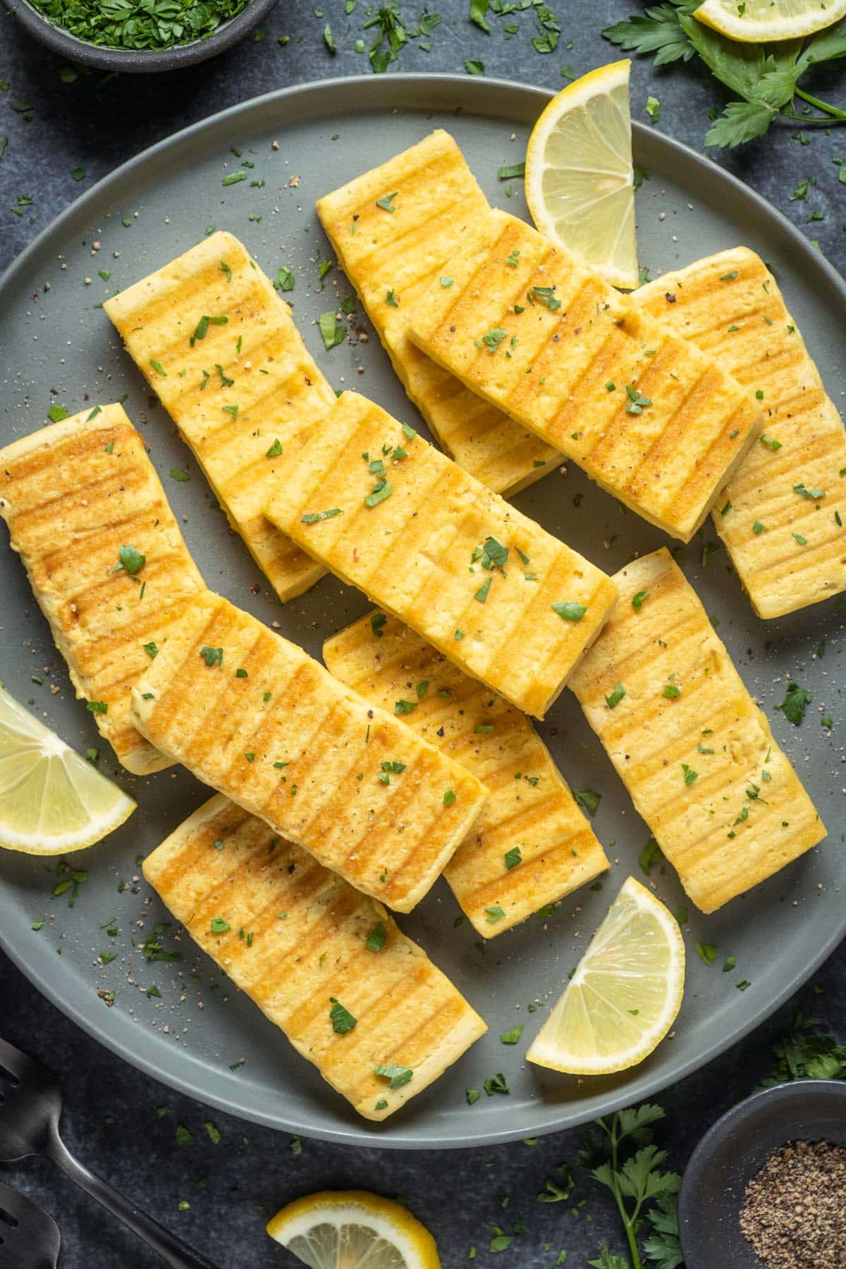 Slices of grilled vegan halloumi on a gray plate. 