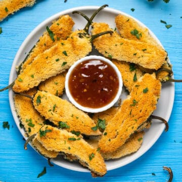 Vegan jalapeño poppers on a white plate with sweet chili sauce.