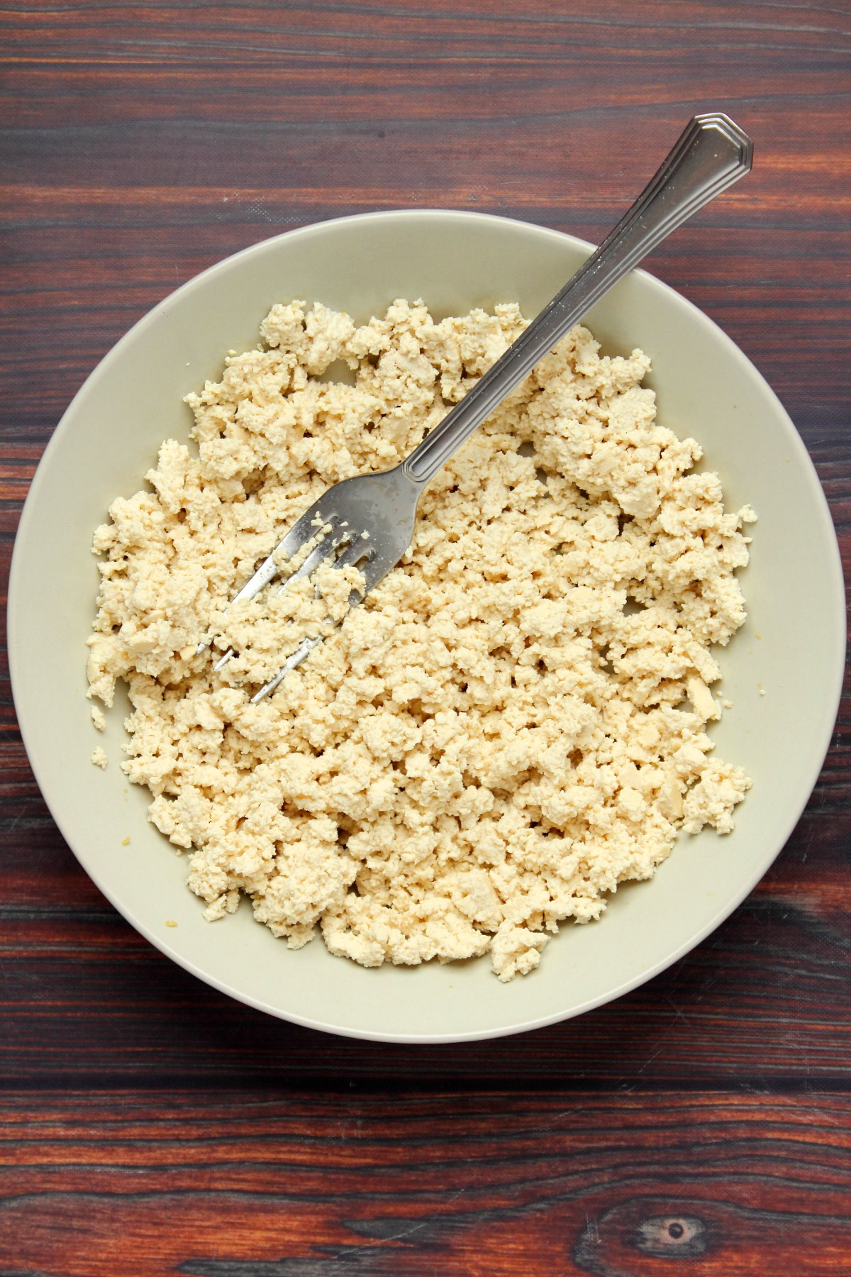 Tofu crumbled with a fork in a bowl.