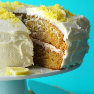 Sliced vegan lemon cake on a white cake stand.