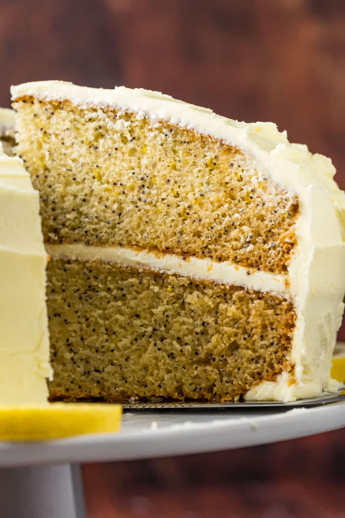 Sliced vegan lemon poppy seed cake on a white cake stand.