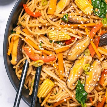 Vegan lo mein in a black bowl with chopsticks.