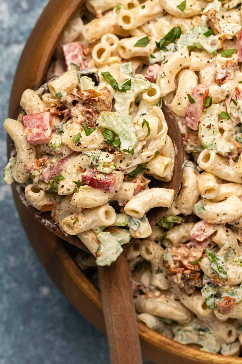 Vegan macaroni salad in a wooden salad bowl with a salad spoon. 