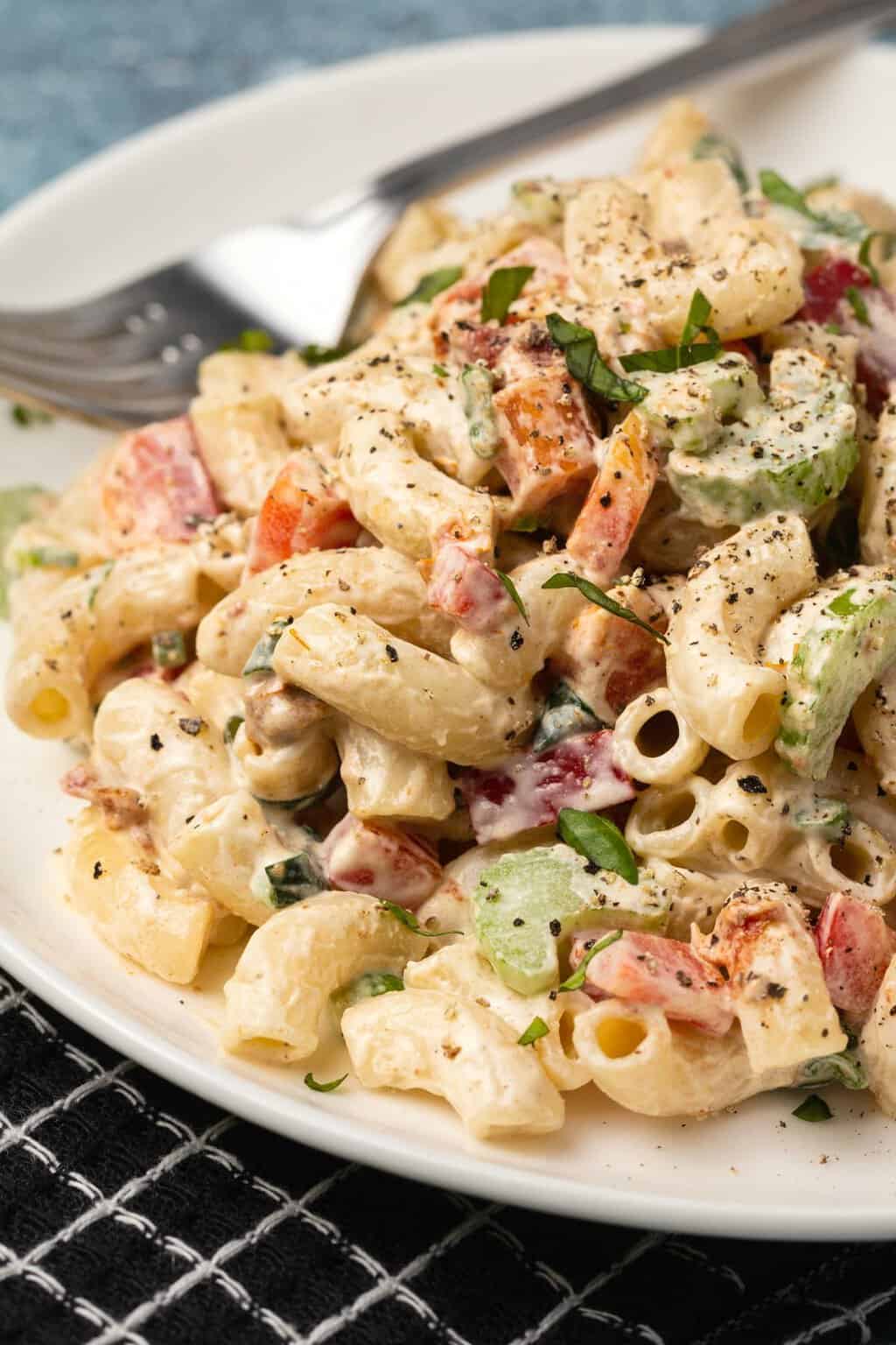 Vegan macaroni salad on a white plate with a fork. 