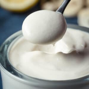 Vegan mascarpone in a glass jar with a teaspoon.