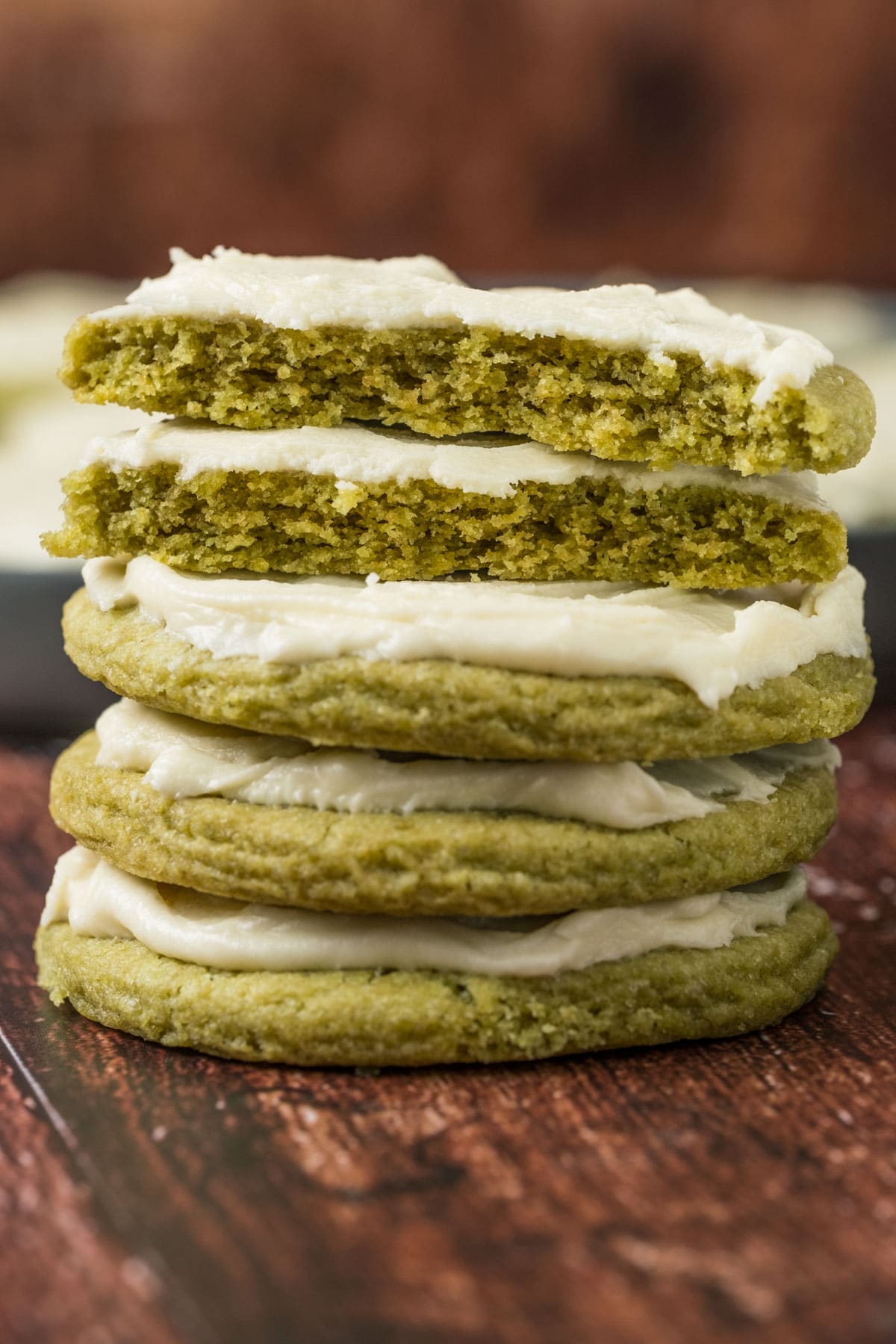 Vegan matcha cookies in a stack with the top cookie broken in half.